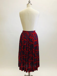 Feminine vintage red pleated skirt with a blue and purple paisley design. Midi length with side zipper closure. Beautiful vintage ribbon on inside hem finishing. A lovely piece for in-between seasons.