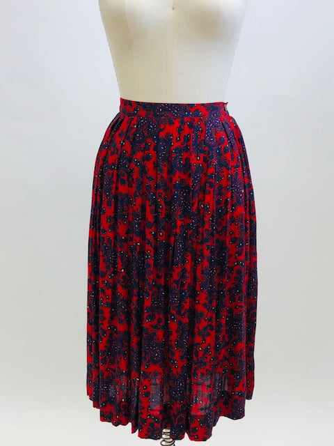 Feminine vintage red pleated skirt with a blue and purple paisley design. Midi length with side zipper closure. Beautiful vintage ribbon on inside hem finishing. A lovely piece for in-between seasons.