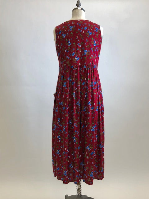 Burgundy sleeveless prairie dress with little blue and white flowers, gathered high doll waist and patch pockets to hold your freshly-picked flowers. Loose fit with double ties at waist to adjust for contouring. Midi length. This adorable dress looks homemade. 