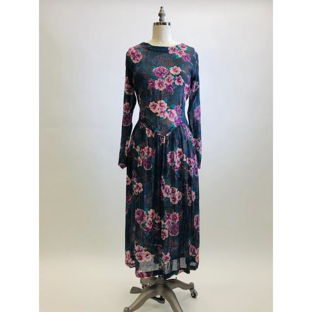 Gorgeous, airy long sleeve dress in purple and blue florals. This is made of a lightweight, sheer fabric so you will want to wear a light slip underneath. It features a v-shaped waistline with gathered skirt, and side seam pockets. The waist can be adjusted with waist ties at back. Button opening at back of bodice with a slight boat neck style. 