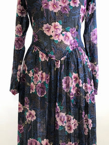 Gorgeous, airy long sleeve dress in purple and blue florals. This is made of a lightweight, sheer fabric so you will want to wear a light slip underneath. It features a v-shaped waistline with gathered skirt, and side seam pockets. The waist can be adjusted with waist ties at back. Button opening at back of bodice with a slight boat neck style. 