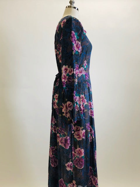 Gorgeous, airy long sleeve dress in purple and blue florals. This is made of a lightweight, sheer fabric so you will want to wear a light slip underneath. It features a v-shaped waistline with gathered skirt, and side seam pockets. The waist can be adjusted with waist ties at back. Button opening at back of bodice with a slight boat neck style. 