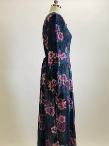 Gorgeous, airy long sleeve dress in purple and blue florals. This is made of a lightweight, sheer fabric so you will want to wear a light slip underneath. It features a v-shaped waistline with gathered skirt, and side seam pockets. The waist can be adjusted with waist ties at back. Button opening at back of bodice with a slight boat neck style. 