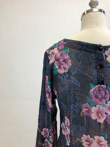 Gorgeous, airy long sleeve dress in purple and blue florals. This is made of a lightweight, sheer fabric so you will want to wear a light slip underneath. It features a v-shaped waistline with gathered skirt, and side seam pockets. The waist can be adjusted with waist ties at back. Button opening at back of bodice with a slight boat neck style. 