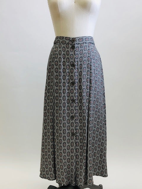 Vintage A-line maxi skirt with buttons down center front and elasticated back waistband in a soft viscose fabric in a white, black and gray regal-style print. Beautifully lightweight for in-between seasons and pairs nicely with t-shirts, sweaters and cardigans. Vintage Timothy Eaton Co. Ltd. label. 