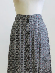 Vintage A-line maxi skirt with buttons down center front and elasticated back waistband in a soft viscose fabric in a white, black and gray regal-style print. Beautifully lightweight for in-between seasons and pairs nicely with t-shirts, sweaters and cardigans. Vintage Timothy Eaton Co. Ltd. label. 