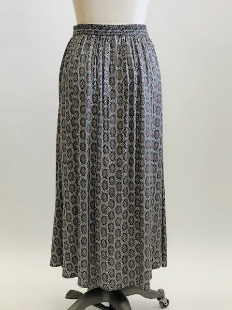 Vintage A-line maxi skirt with buttons down center front and elasticated back waistband in a soft viscose fabric in a white, black and gray regal-style print. Beautifully lightweight for in-between seasons and pairs nicely with t-shirts, sweaters and cardigans. Vintage Timothy Eaton Co. Ltd. label. 