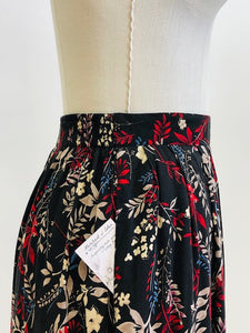 Vintage rayon maxi skirt with pleats at waistband featuring red, taupe and beige foliage and floral print against black background. Side seam pockets, and elasticated waistband in the back. Beautiful as an in-between seasons skirt and for a fall walk with tights and little boots.