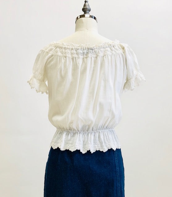 Adorable soft off-white top in a cotton/silk blend with elasticated peplum waist and neckline. This top features feminine eyelet detailing along the neckline, sleeve and waist hem, and pairs nicely with high waisted trousers, or a romantic linen skirt.