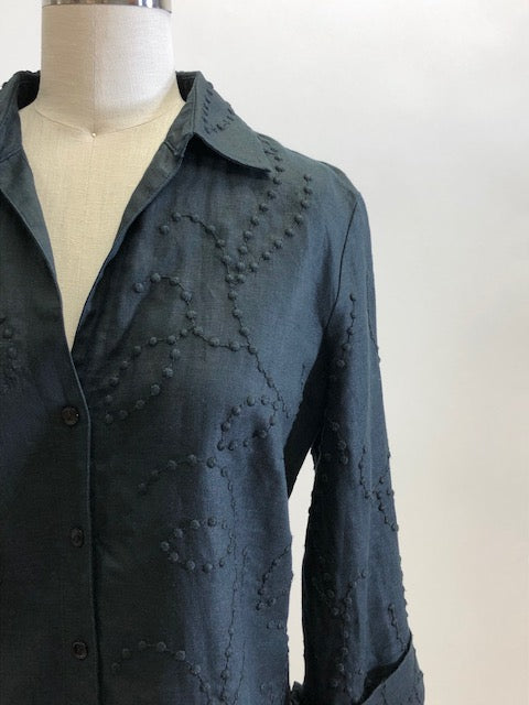 Black linen 3/4 sleeve button-down top with a textured design and folded sleeve cuff. Relaxed fit, versatile for in-between seasons, and sweet when paired with vintage Levi's or cropped chinos.