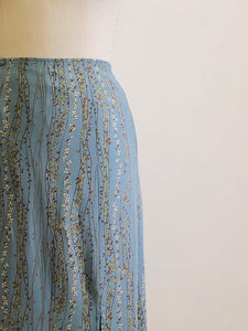 Romantic powder blue maxi skirt with delicate field vines. Lined skirt with front slit, side waist ties and back zipper closure.  