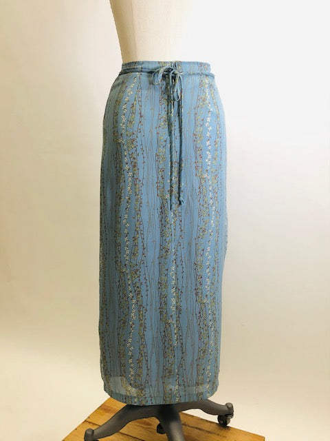 Romantic powder blue maxi skirt with delicate field vines. Lined skirt with front slit, side waist ties and back zipper closure.  