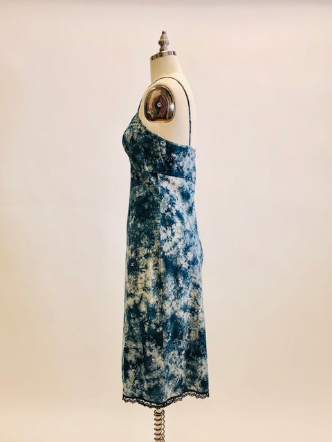 Holt Renfrew Studio cotton slip midi dress in tie-dye indigo print with spaghetti straps, feminine lace hem trim, empire bust style, and center back zipper closure. 