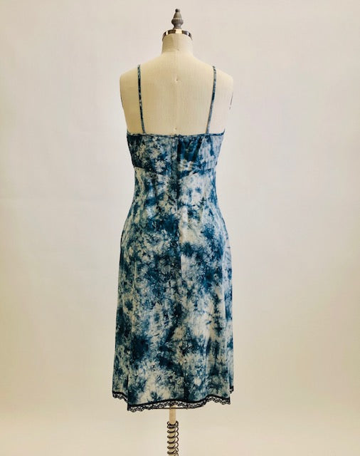 Holt Renfrew Studio cotton slip midi dress in tie-dye indigo print with spaghetti straps, feminine lace hem trim, empire bust style, and center back zipper closure. 