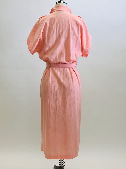 Vintage pink button down long dress with kimono sleeves with an 80s style loose fit on top and side seam pockets. Interesting asymmetrical design-shaped bust pockets. Comes with matching belt. Fabric is unknown, has a textured feel, could be a viscose/cotton blend. 