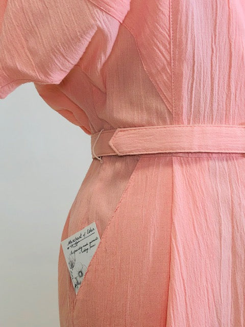 Vintage pink button down long dress with kimono sleeves with an 80s style loose fit on top and side seam pockets. Interesting asymmetrical design-shaped bust pockets. Comes with matching belt. Fabric is unknown, has a textured feel, could be a viscose/cotton blend. 