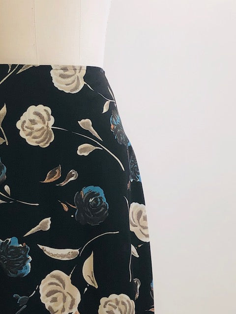 Vintage classic 90s black floral maxi skirt with a soft A-line silhouette, accented with teal and cream floral print. Unlined with center back zipper closure. 