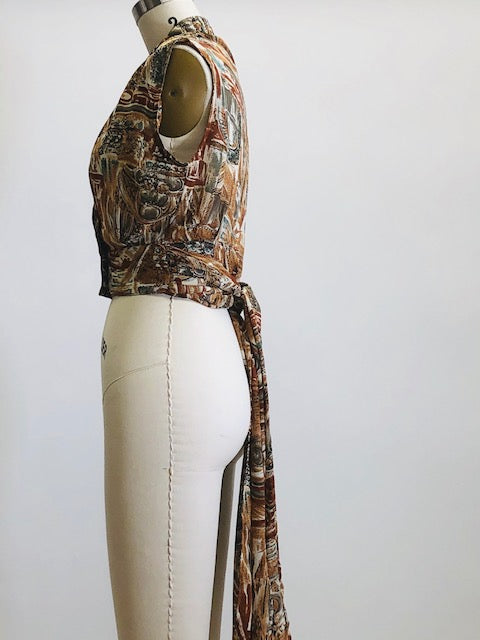 Vintage 90s short-waisted sleeveless wrap tie blouse with crossover button enclosure. Fabric pattern looks like European architectural shapes in brown tones. This top pairs nicely with high-waisted shorts or pants.