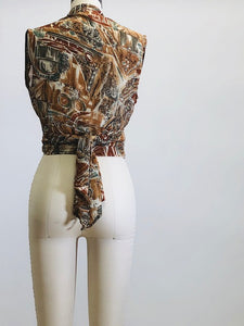 Vintage 90s short-waisted sleeveless wrap tie blouse with crossover button enclosure. Fabric pattern looks like European architectural shapes in brown tones. This top pairs nicely with high-waisted shorts or pants.