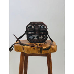 Special treasure box purse in octagonal shape with embroidered surfacing detail, brown leather and brown tones with long adjustable strap, and magnetic snap enclosure. 