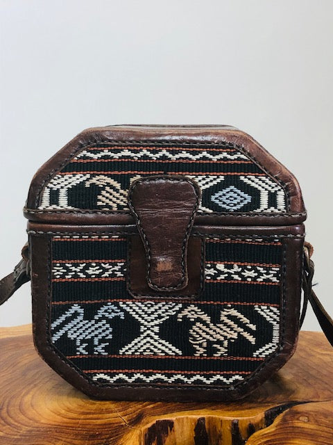 Special treasure box purse in octagonal shape with embroidered surfacing detail, brown leather and brown tones with long adjustable strap, and magnetic snap enclosure. 