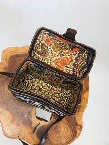 Special treasure box purse in octagonal shape with embroidered surfacing detail, brown leather and brown tones with long adjustable strap, and magnetic snap enclosure. 