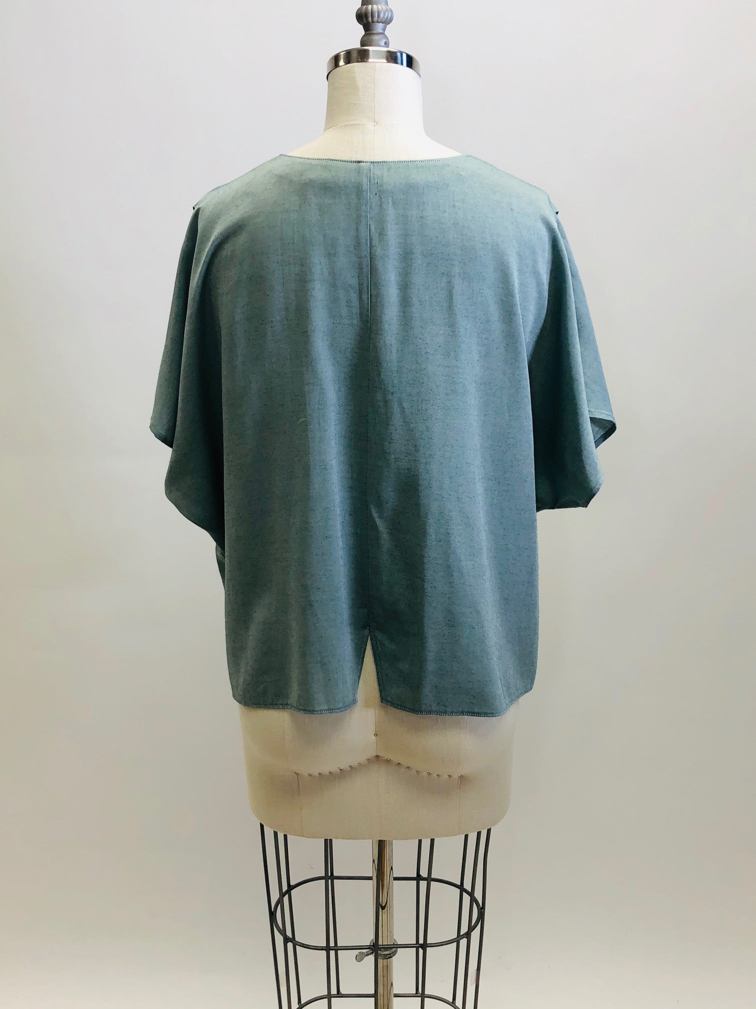 Vintage loose-fitting box shape top with button-down front, short kimono sleeve with interesting shoulder pleat detail. Sage green fabric with slight sheen. Worn like a one-size fits all style; great for tucking into linen trousers or shorts. 